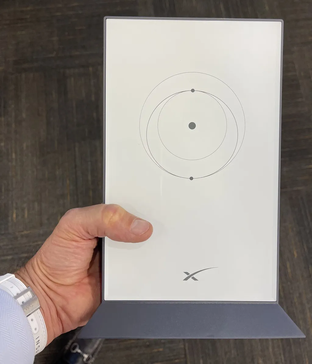 A hand holding a white Starlink user terminal bearing the SpaceX logo