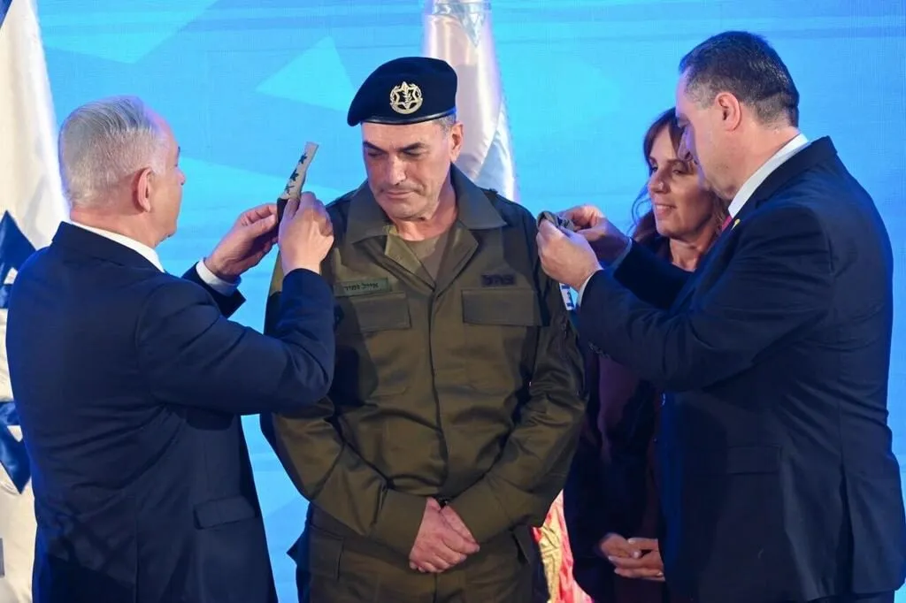 Benjamin Netanyahu stands with IDF chief Eyal Zamir at a ceremony in front of Israeli flags