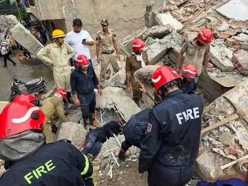 Fire and rescue personnel searching rubble after a building collapse in Delhi