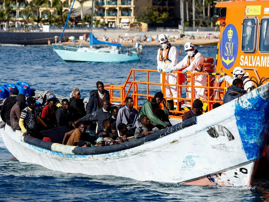 Migrants aboard a small boat alongside a Spanish rescue vessel at sea
