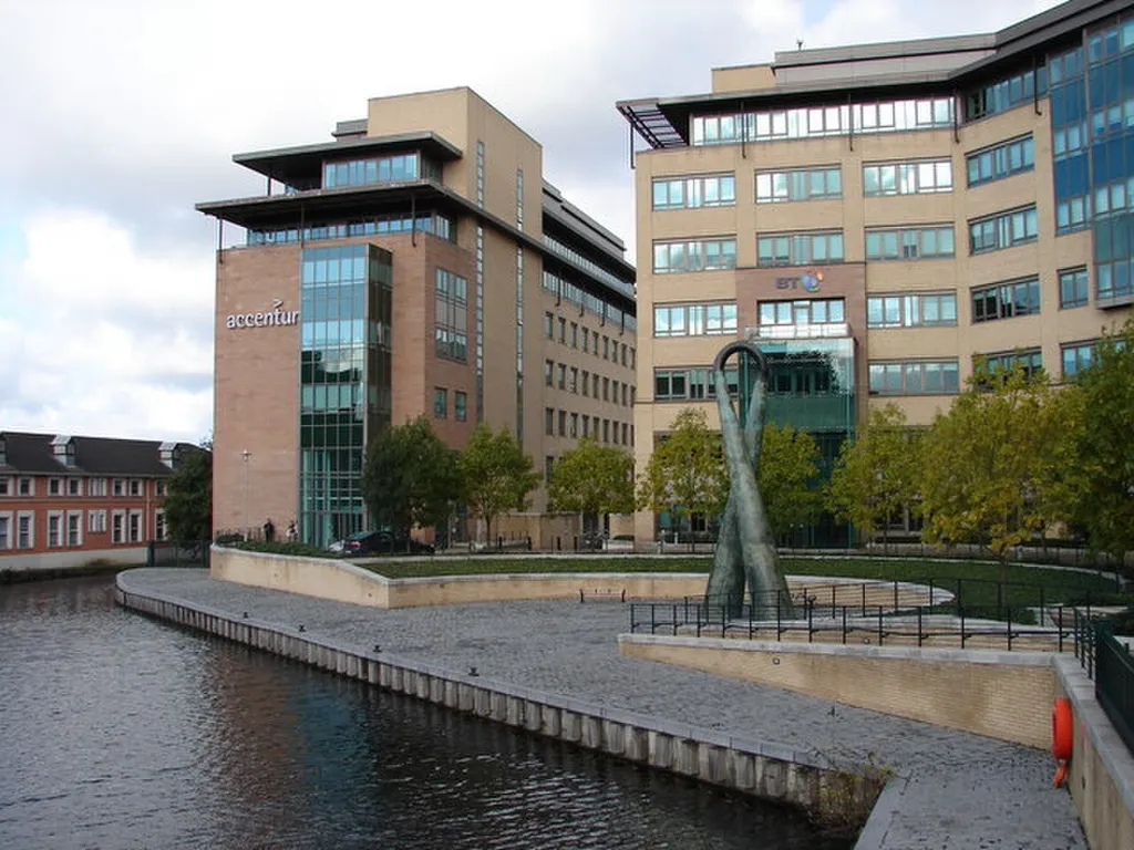 Accenture-branded office building on Dublin's Grand Canal with a public sculpture in the foreground