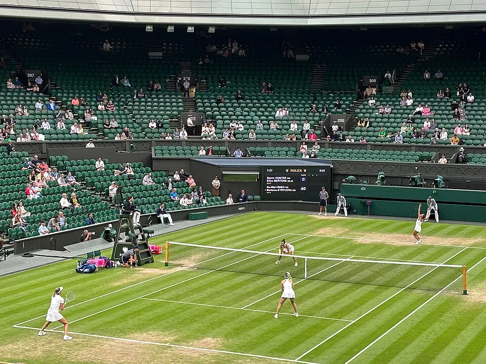 Four players contesting a doubles match on a grass court at Wimbledon during the 2023 women's doubles final.