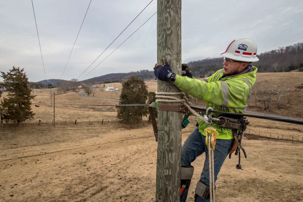 A contract lineman climbing a wooden utility pole to install fibre-optic cable for Virginia’s BARC Electric Cooperative in rural Lexington