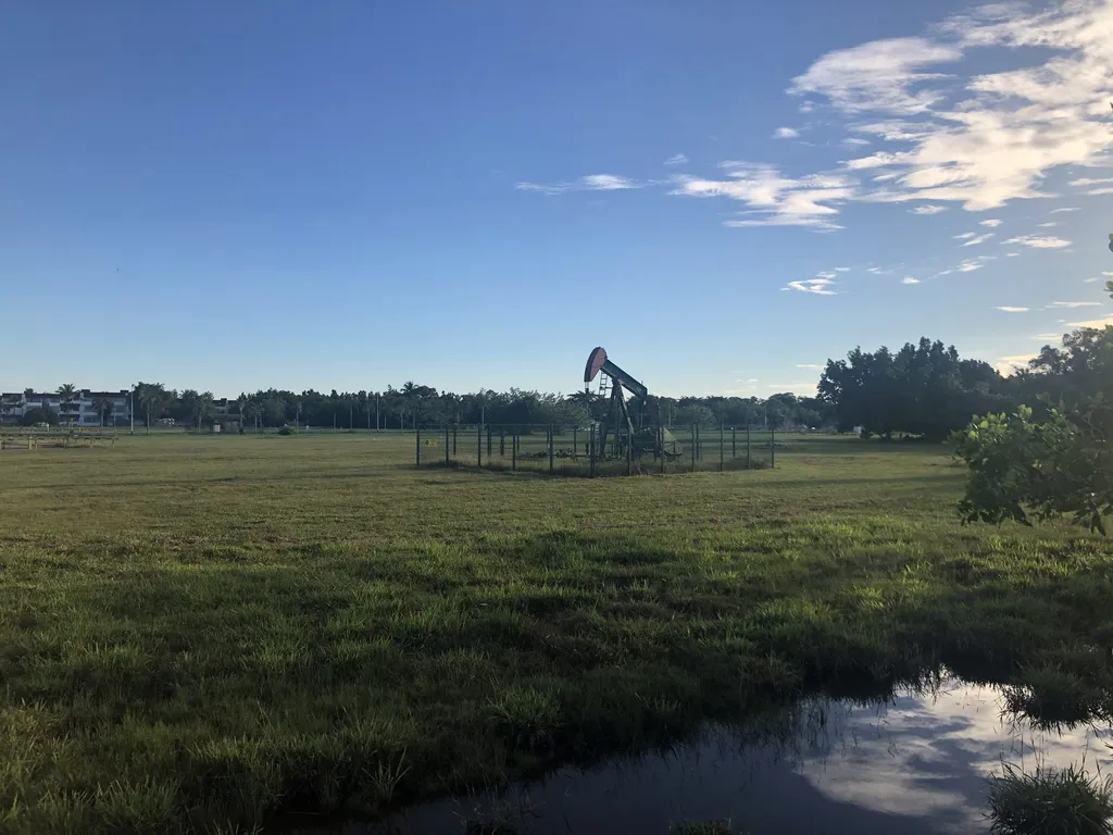 An oil pumpjack standing in a grassy field near the Billionth Barrel Monument in Seria, Brunei.