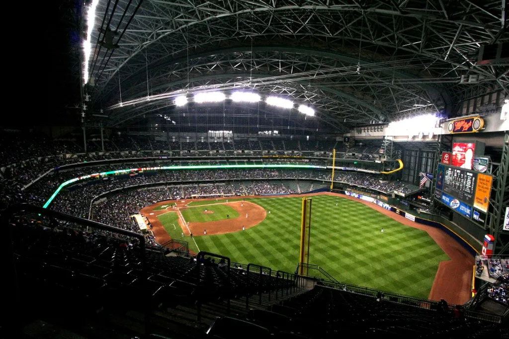 Night-time wide view of American Family Field (formerly Miller Park) in Milwaukee during a Brewers home game, with a packed crowd under the closed retractable roof.