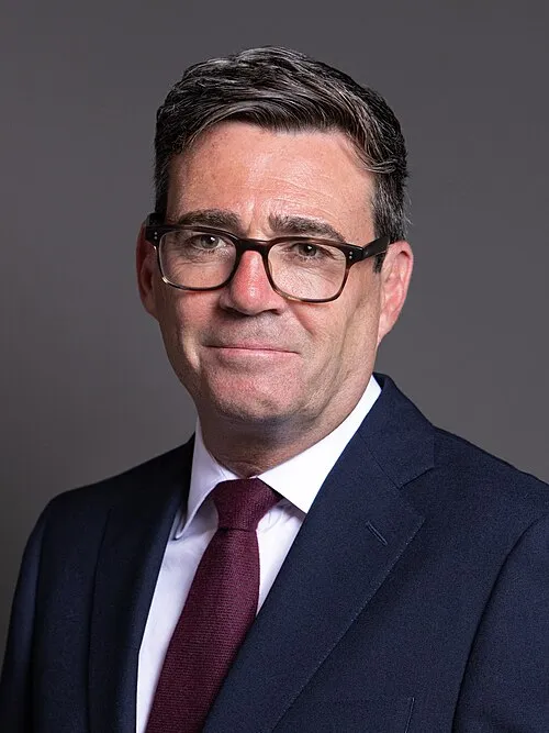Andy Burnham in his official 2026 House of Commons portrait, wearing glasses, dark suit and burgundy tie.