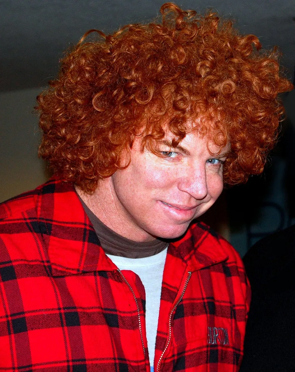 Portrait of comedian Carrot Top (Scott Thompson), smiling, with his signature red curly hair