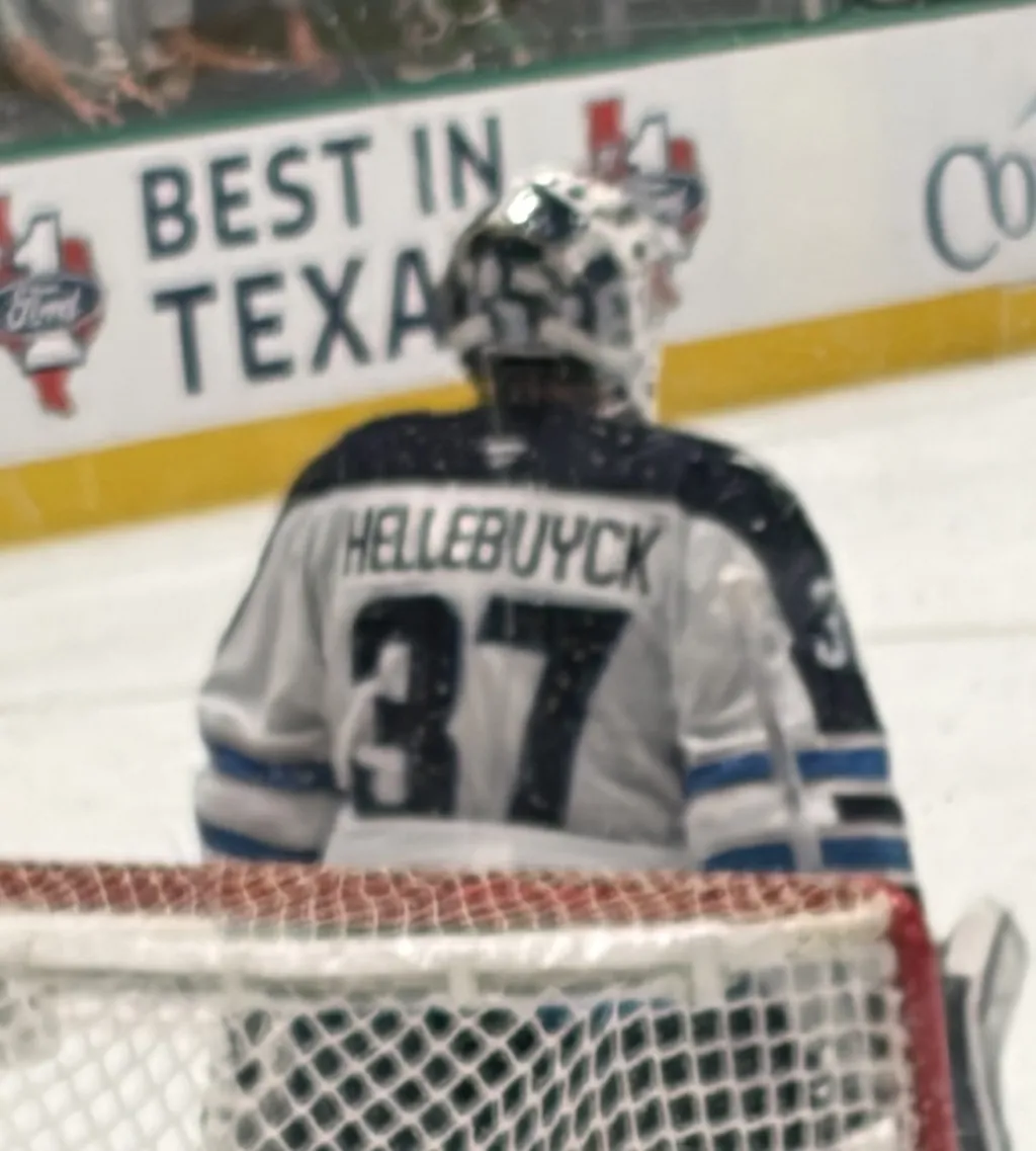 Connor Hellebuyck in his Winnipeg Jets crease, seen from behind with his nameplate and number 37 visible