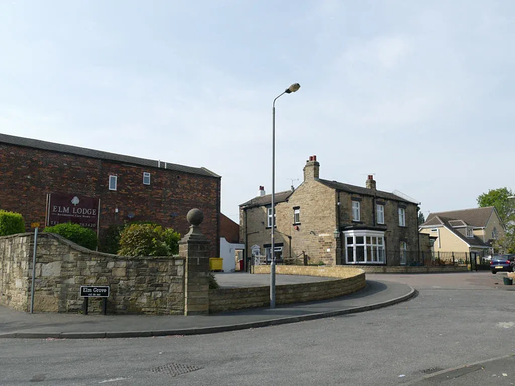 Exterior of Elm Lodge residential care home at Elm Grove, Horbury, behind a stone wall and gated entrance