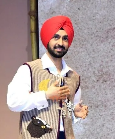 Diljit Dosanjh wearing a red turban and knit vest at the Amar Singh Chamkila trailer launch.