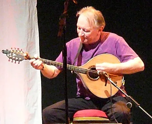 Dónal Lunny playing the bouzouki on stage at Bristol in 2012, wearing a purple shirt