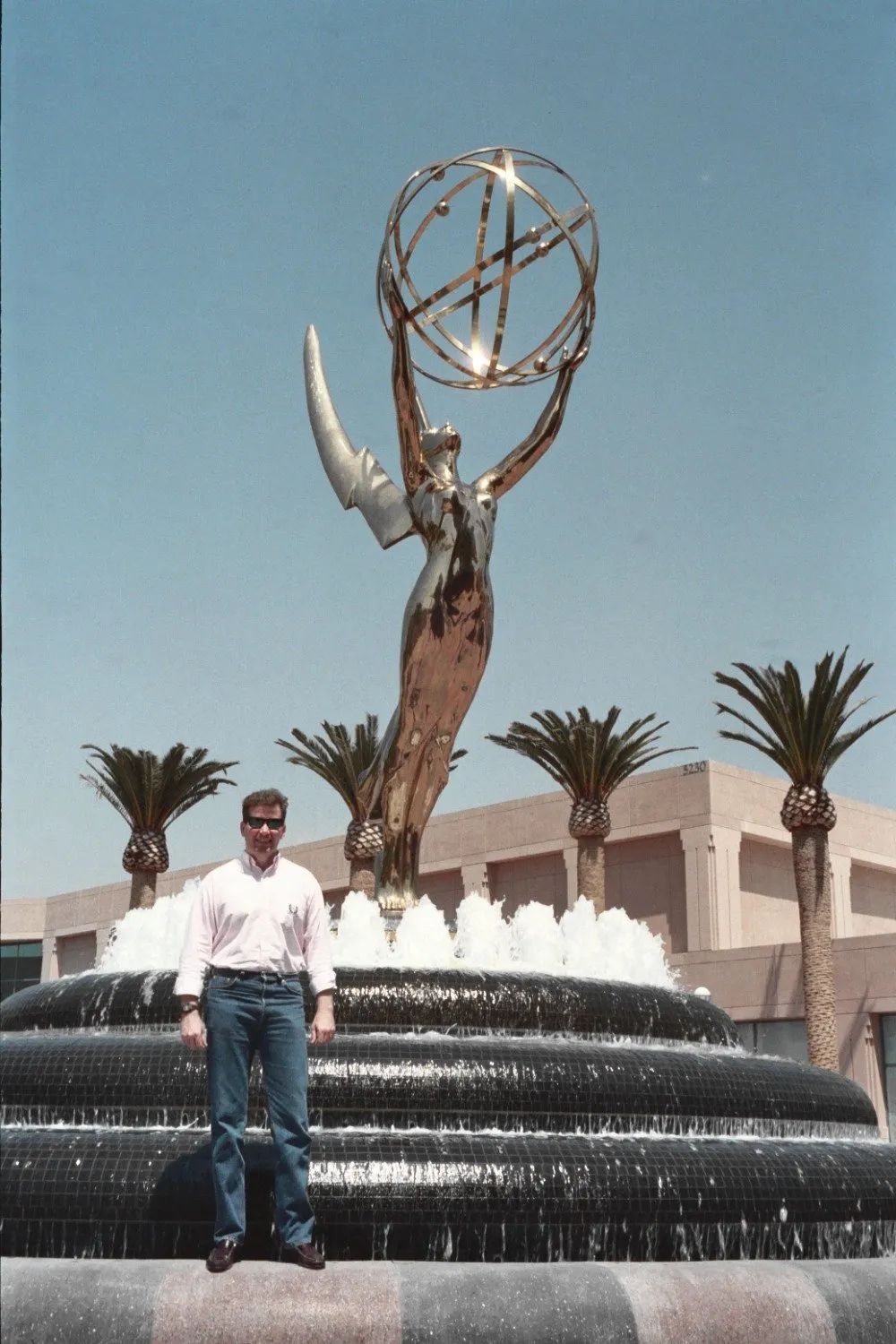 Giant Emmy Award statue at the Television Academy fountain in North Hollywood, held aloft against a clear sky.