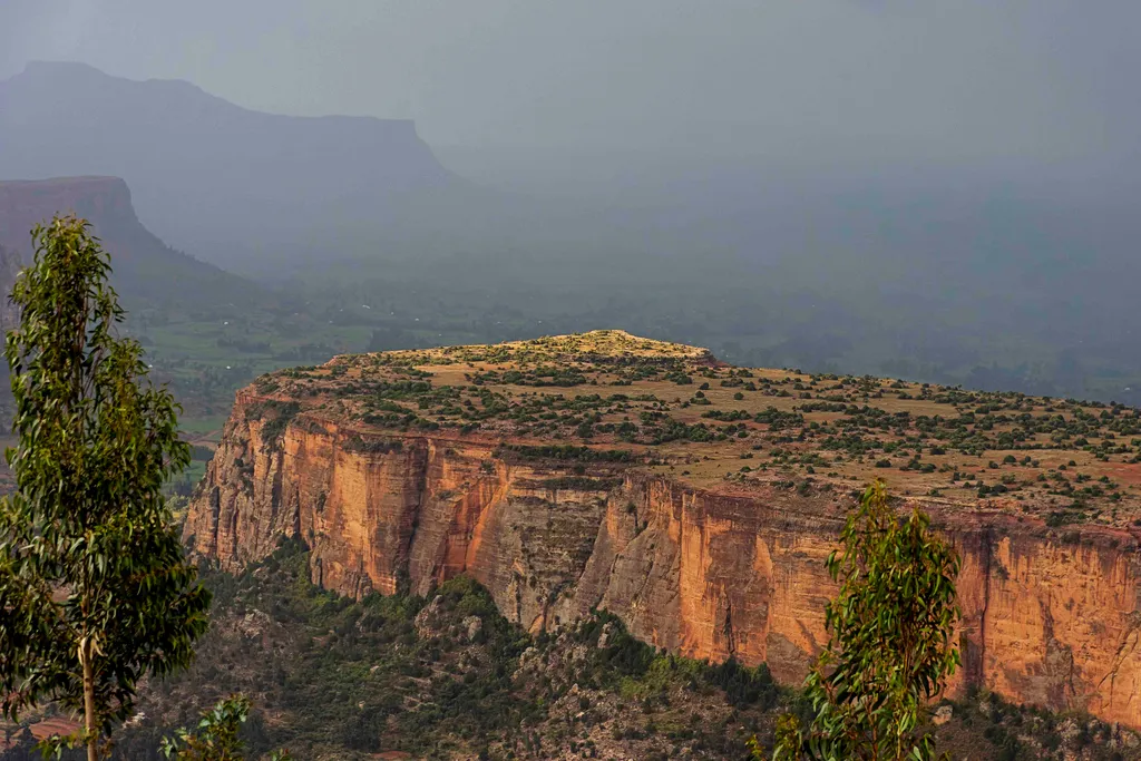 The dramatic cliff-edged highlands of Tigray, Ethiopia, with layered rock formations under a hazy sky.