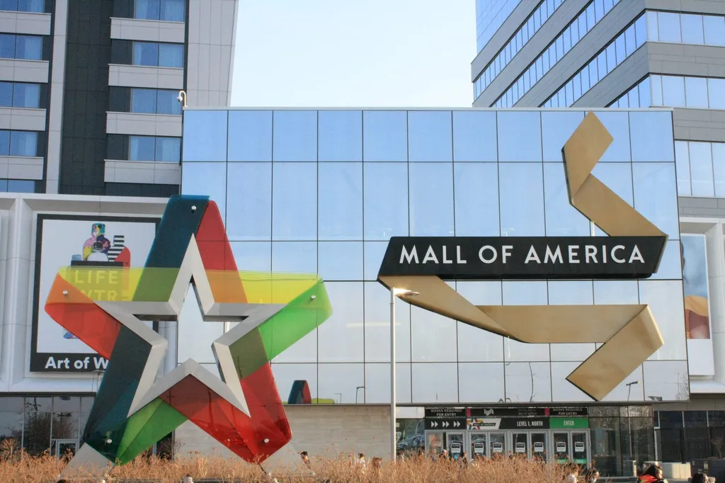 The Mall of America's front entrance in Bloomington, Minnesota, with the large multicolored star sculpture and a black banner reading MALL OF AMERICA above the Level 1 North entry doors.