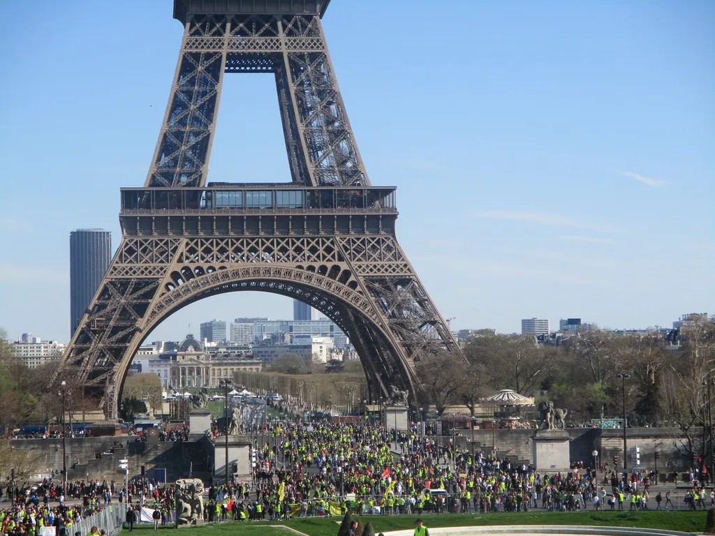 A large crowd of Yellow Vest (gilets jaunes) protesters wearing high-visibility vests gathered at the Trocadéro in Paris beneath the Eiffel Tower