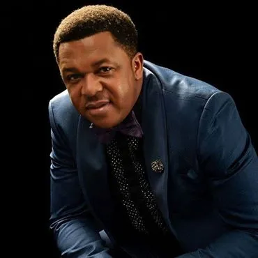 Studio portrait of Nigerian Nollywood actor Francis Duru in a navy suit and bow tie