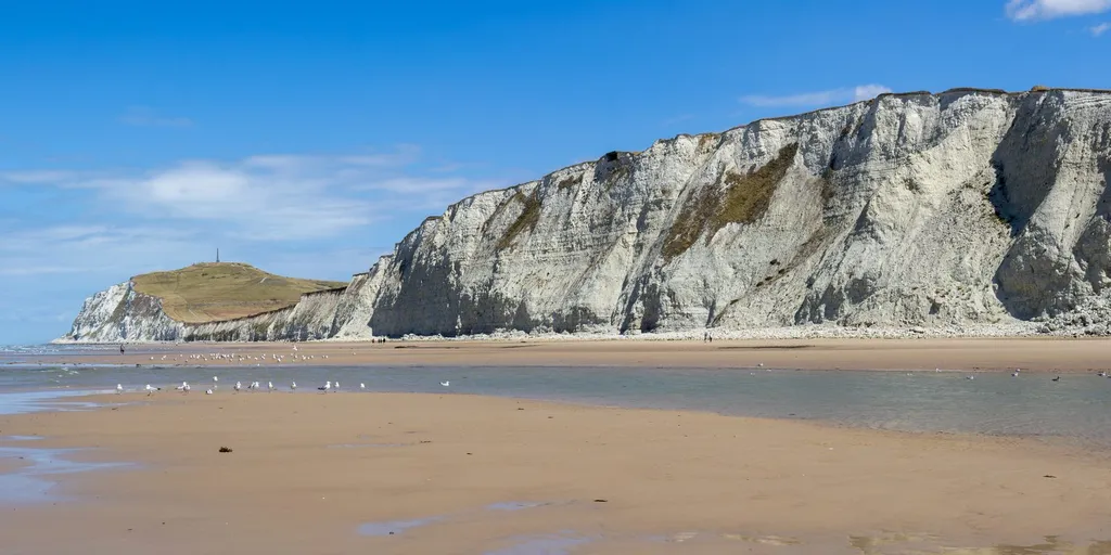 The white cliffs of Cap Blanc-Nez rising above a sandy beach near Calais, northern France, on the coast where small boats set off to cross the Channel