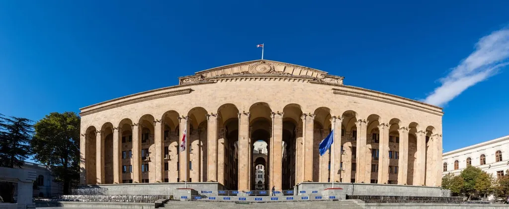 The colonnaded Parliament of Georgia building in Tbilisi flying the Georgian and EU flags