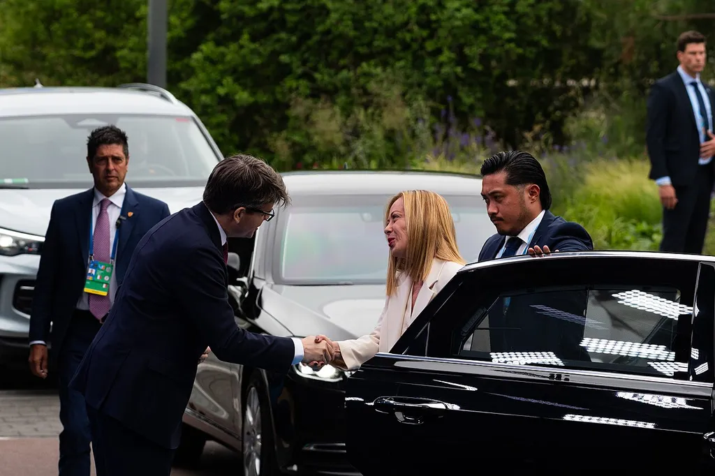 Giorgia Meloni, Italy's prime minister, arriving at the 2025 NATO Summit in The Hague, shaking hands as she steps out of her car.