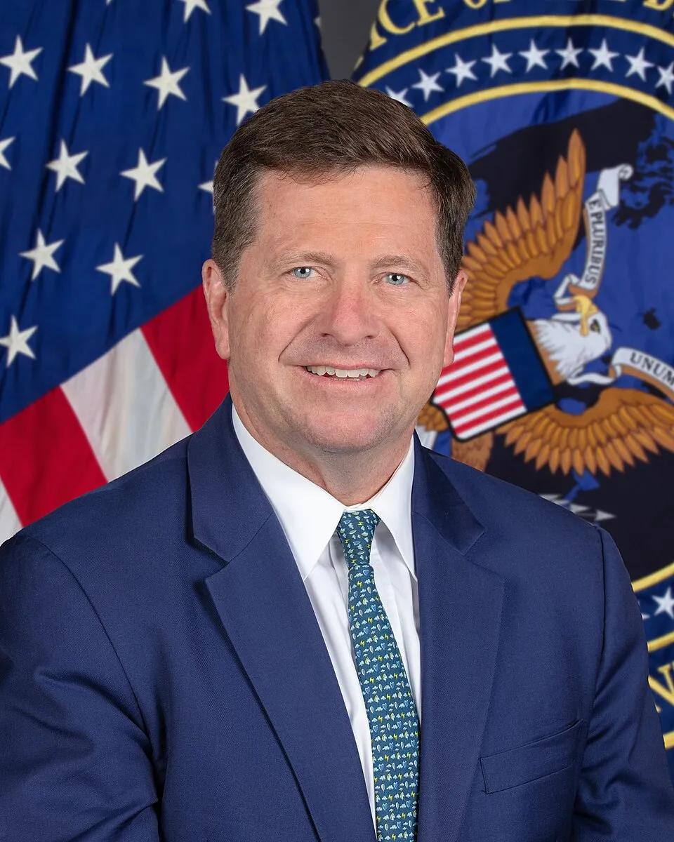 Official 2026 portrait of Director of National Intelligence Jay Clayton, standing before the US flag and the DNI seal.