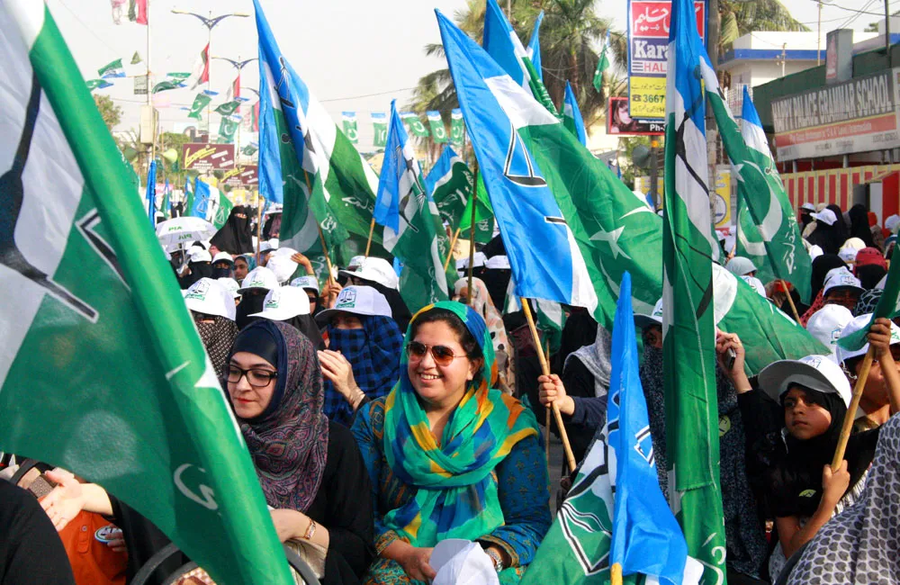 Jamaat-e-Islami supporters waving green and white party flags at a rally in Karachi, Pakistan.