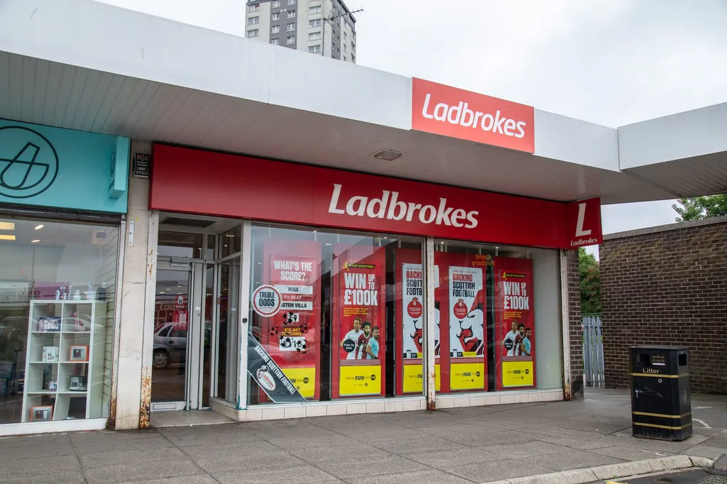 A Ladbrokes betting shopfront in Knightswood with red branding and football betting promotions displayed in the windows