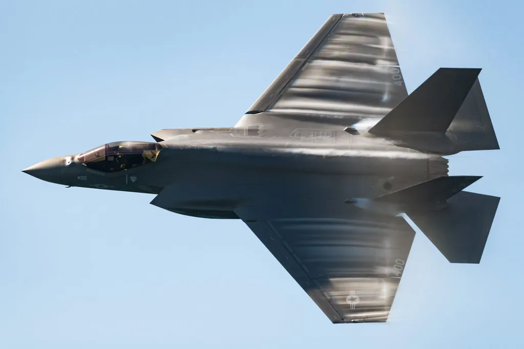 A US Navy F-35C Lightning II fighter jet banks during a flight demonstration at the 2021 Pacific Airshow, leaving vapour trails.
