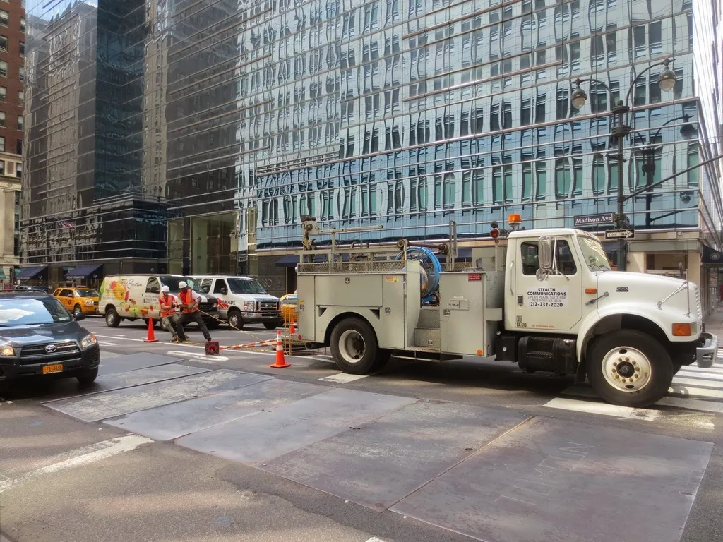 Fiber-optic cable being pulled by a broadband installation crew at a street worksite