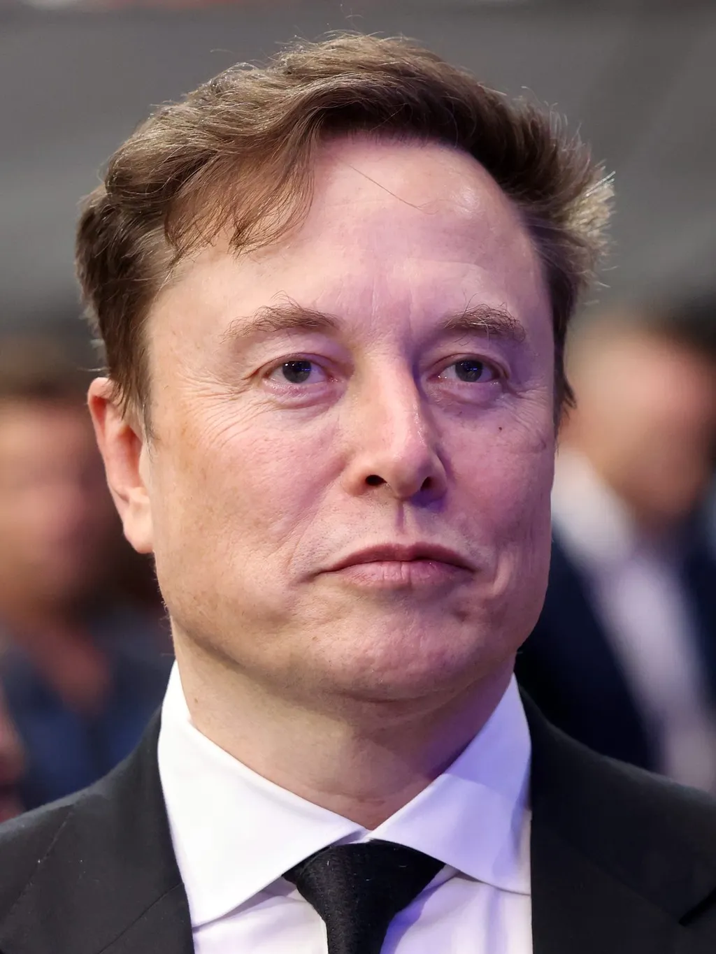Elon Musk in a dark suit and tie at a public event