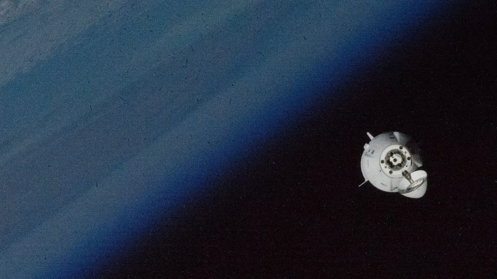 SpaceX Crew Dragon capsule approaching the International Space Station against Earth's limb.
