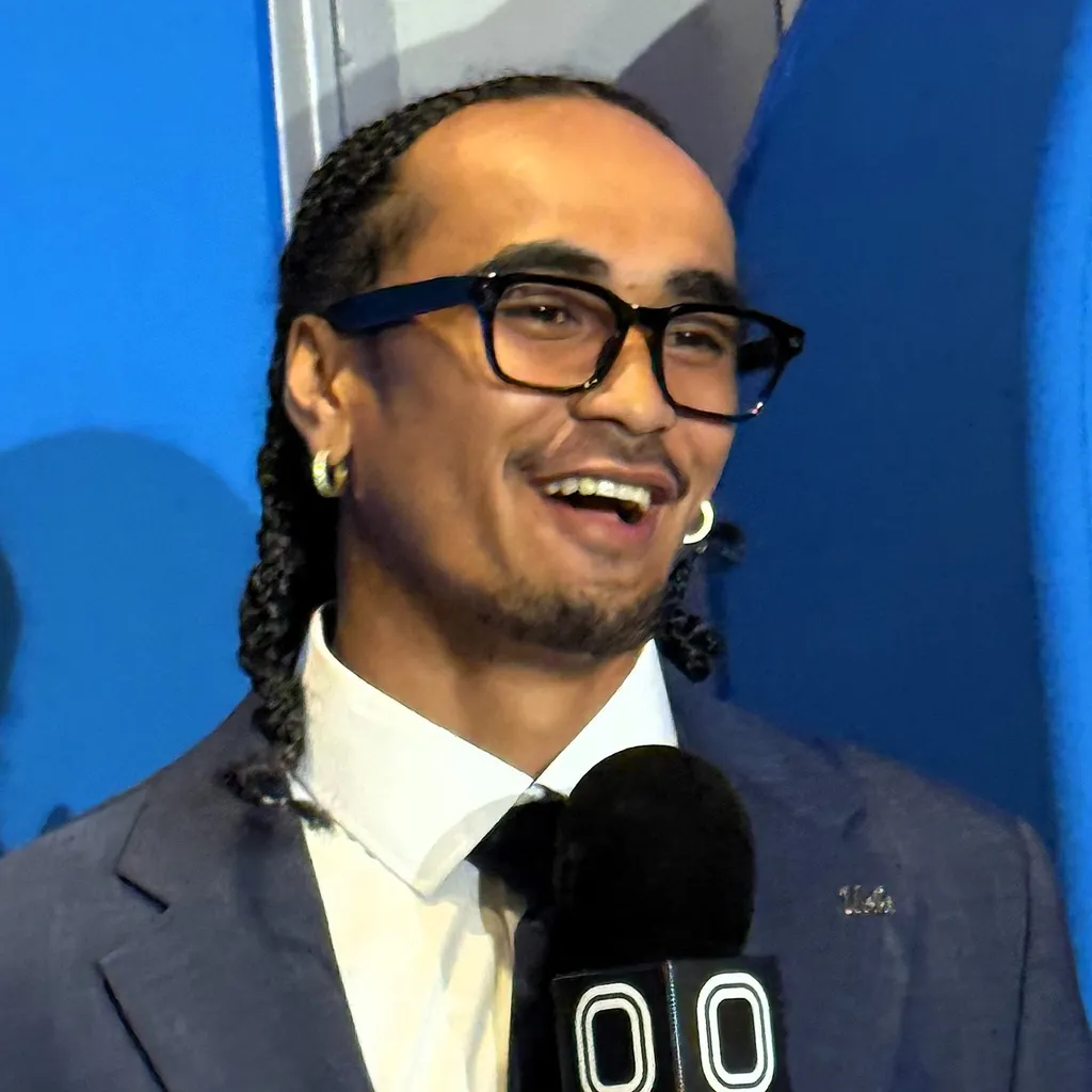 UCLA quarterback Nico Iamaleava wearing glasses with a UCLA pin, speaking at a podium at the 2026 Big Ten Media Day.
