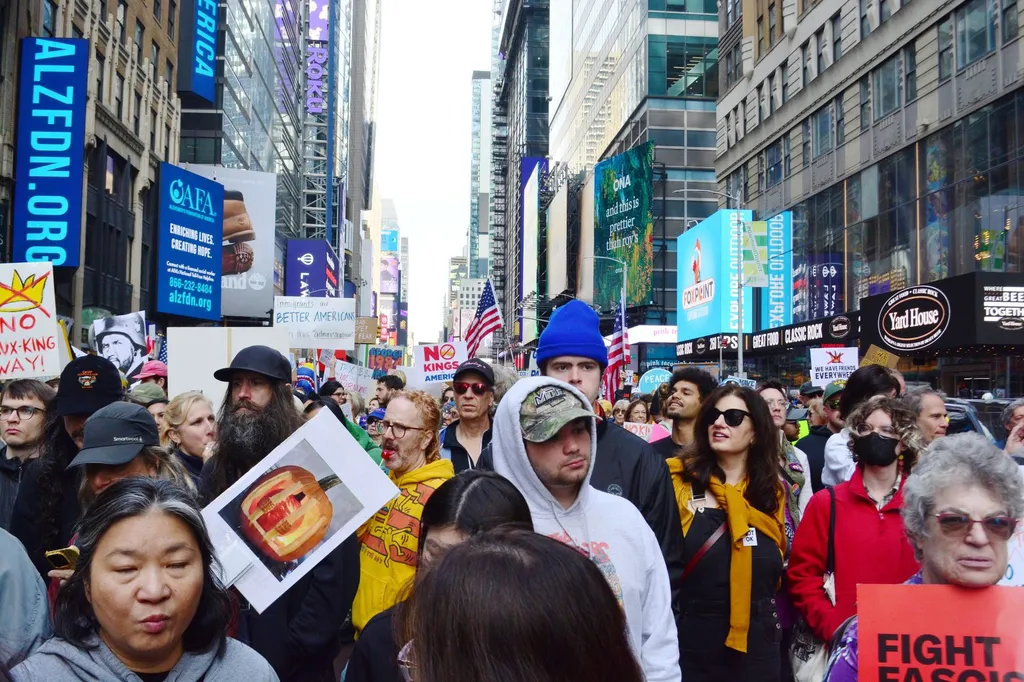 Demonstrators fill Seventh Avenue in Manhattan carrying yellow 'No Kings' signs during the October 2025 No Kings protest march