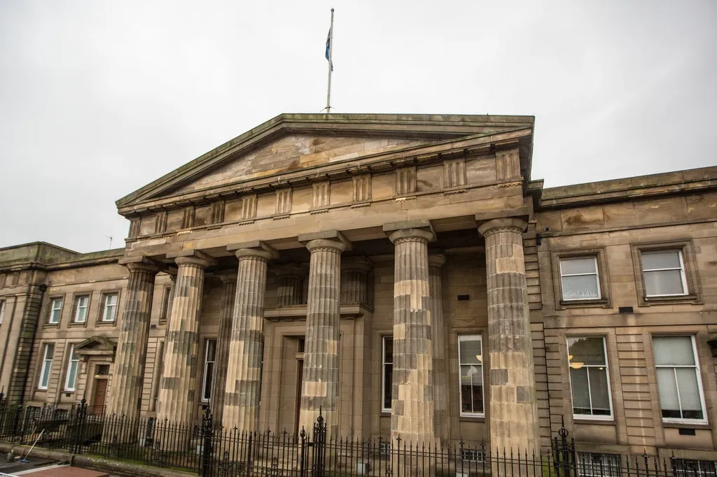 The neoclassical portico of the High Court of Justiciary on Saltmarket, Glasgow, with its fluted Doric columns and a Saltire flying above — the court where Paul Ferris was acquitted in 1992.