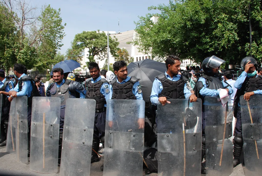 Pakistani police officers in riot gear holding shields, stationed outside the Supreme Court building in Islamabad.