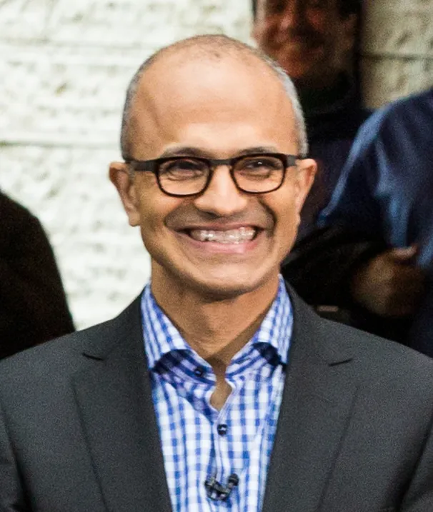 Microsoft chief executive Satya Nadella smiling, wearing glasses, a suit and a checked shirt