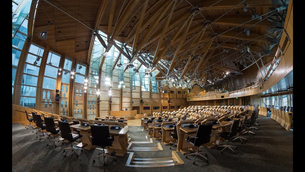 The empty debating chamber of the Scottish Parliament at Holyrood, with its distinctive wooden roof beams.