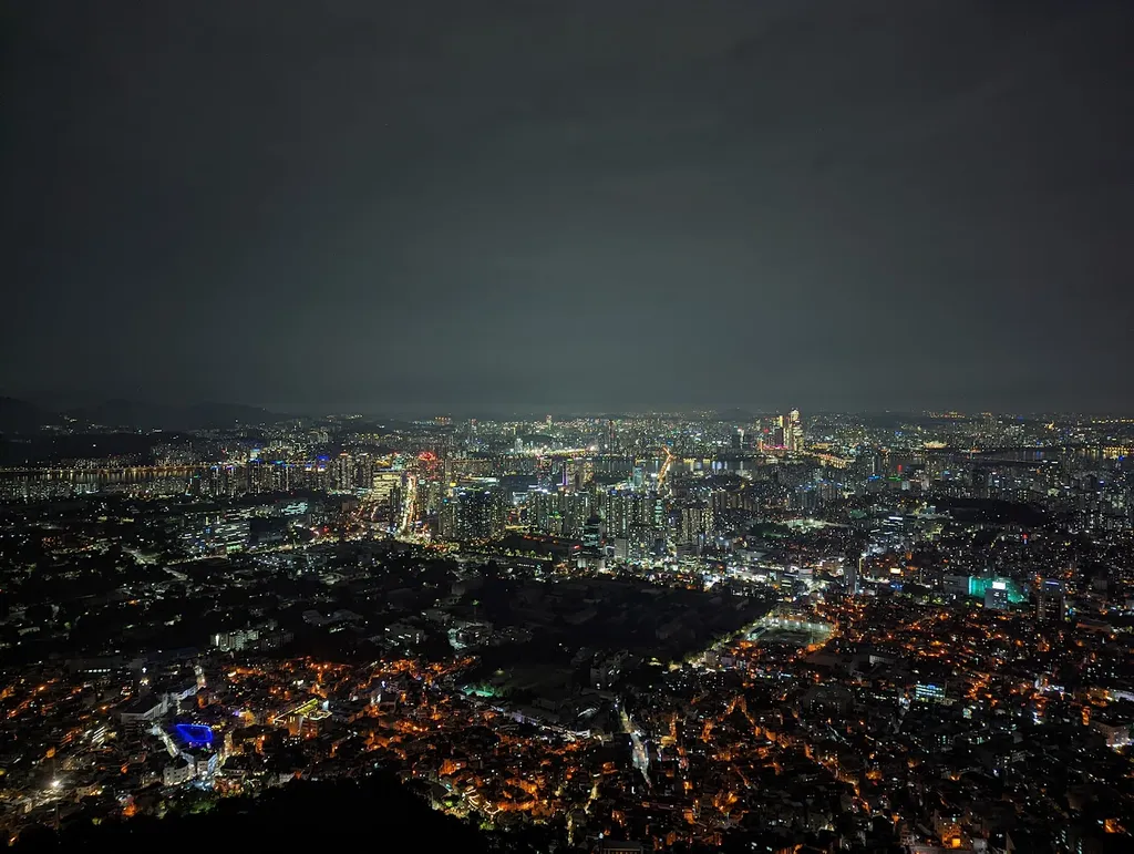 Night-time panoramic view of the Seoul skyline, with the city's dense lights spreading toward the horizon