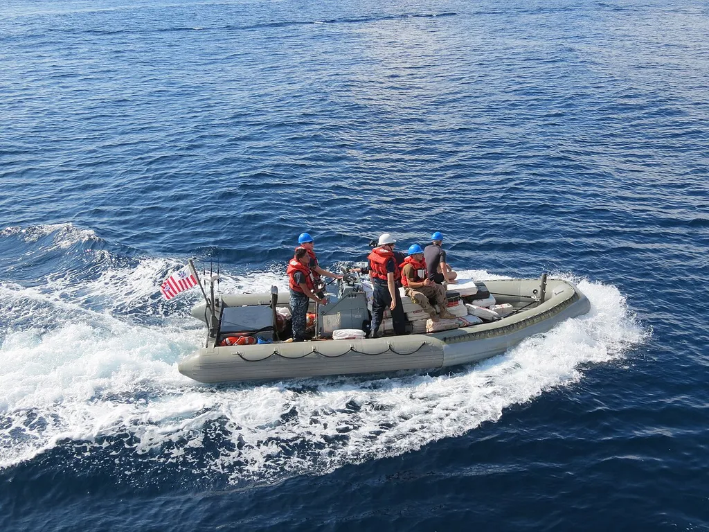A U.S. Coast Guard boarding team at sea with bales of seized cocaine.