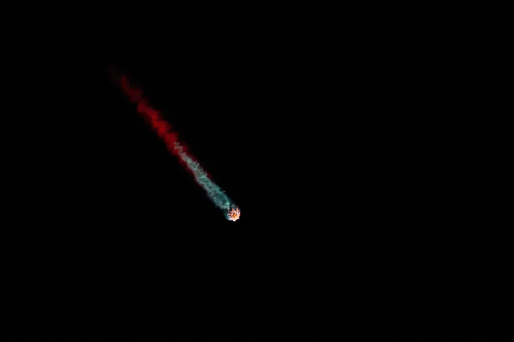 A Falcon 9 rocket carrying Starlink satellites ascends through the night sky, trailing fire and exhaust in this file photo.