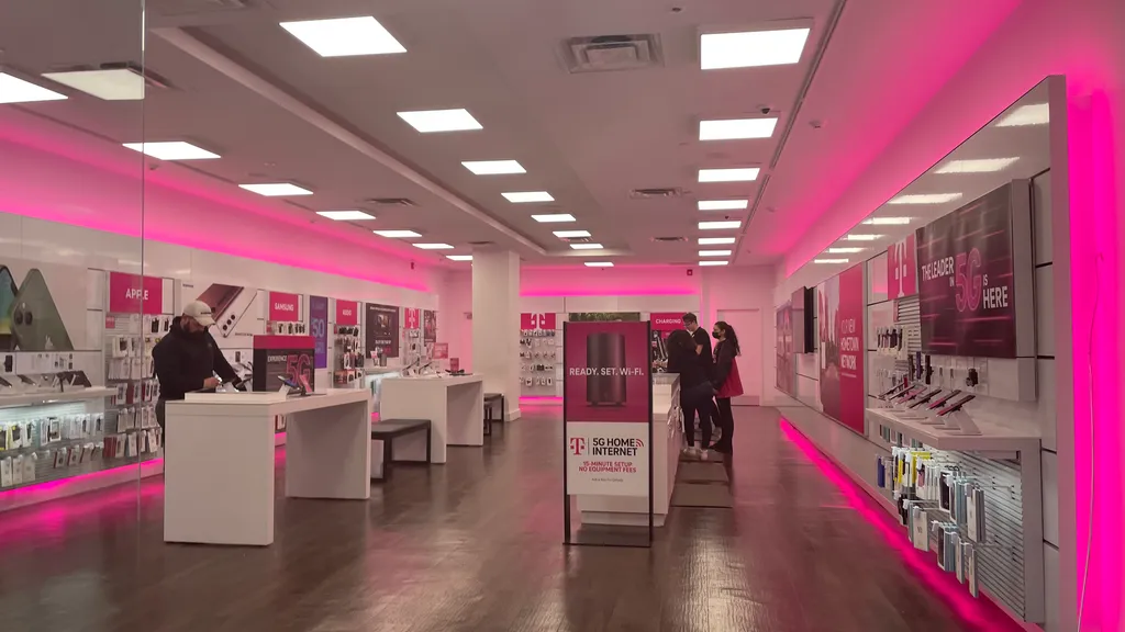 Interior of a T-Mobile retail store with signature magenta lighting, phone displays and 5G signage