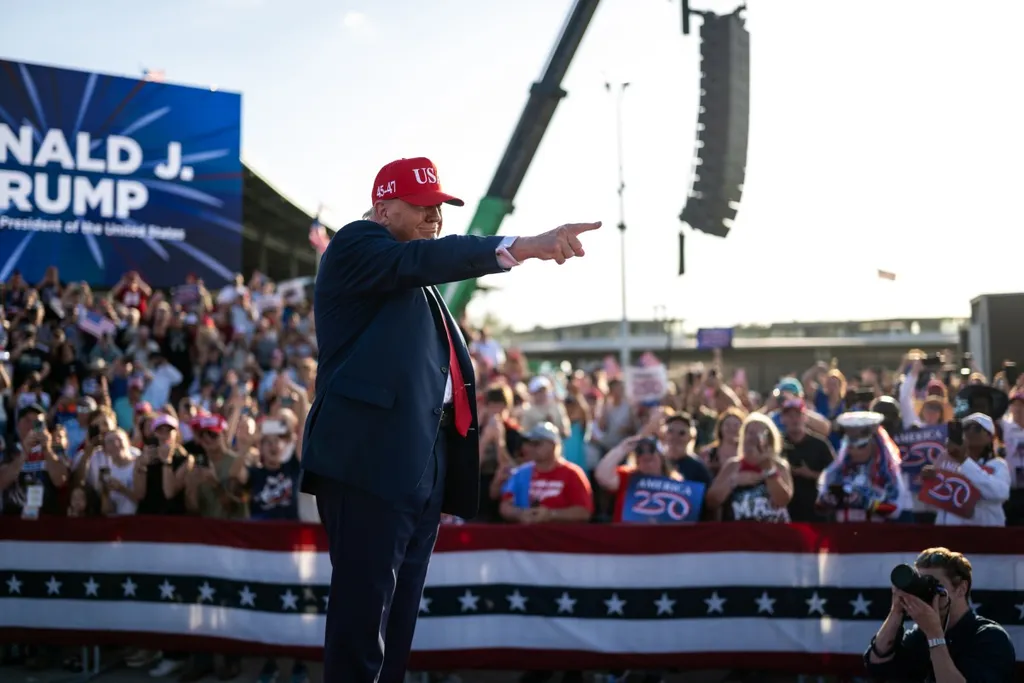 Donald Trump in a red 45-47 cap pointing to supporters at a campaign rally