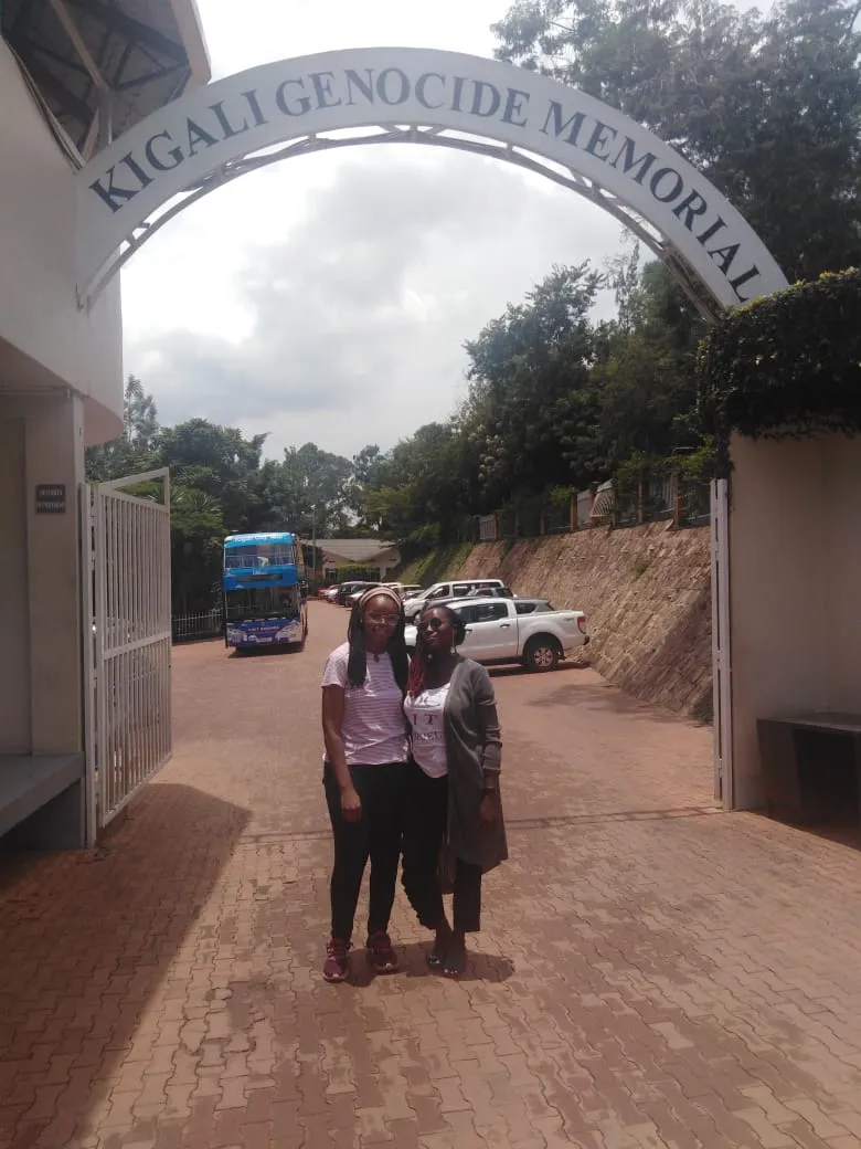 Two visitors standing beneath the entrance arch of the Kigali Genocide Memorial in Rwanda.