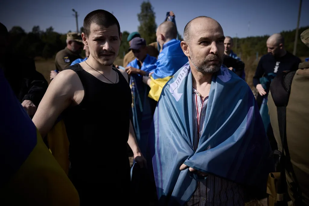 Freed Ukrainian servicemen wrapped in Ukrainian flags after a prisoner exchange with Russia. Photo: President of Ukraine press service, via Wikimedia Commons (CC0).
