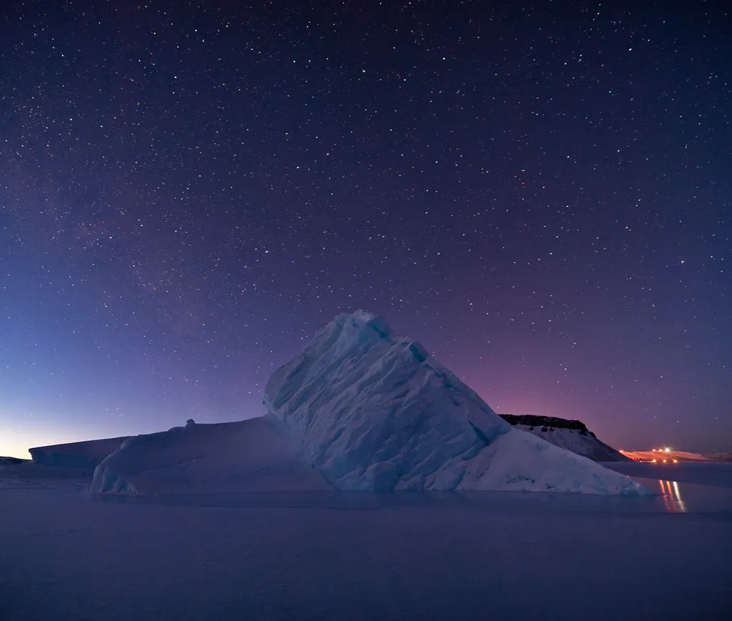 Aerial view of a large tabular iceberg in icy waters with the Greenland coastline in the distance (file photo)