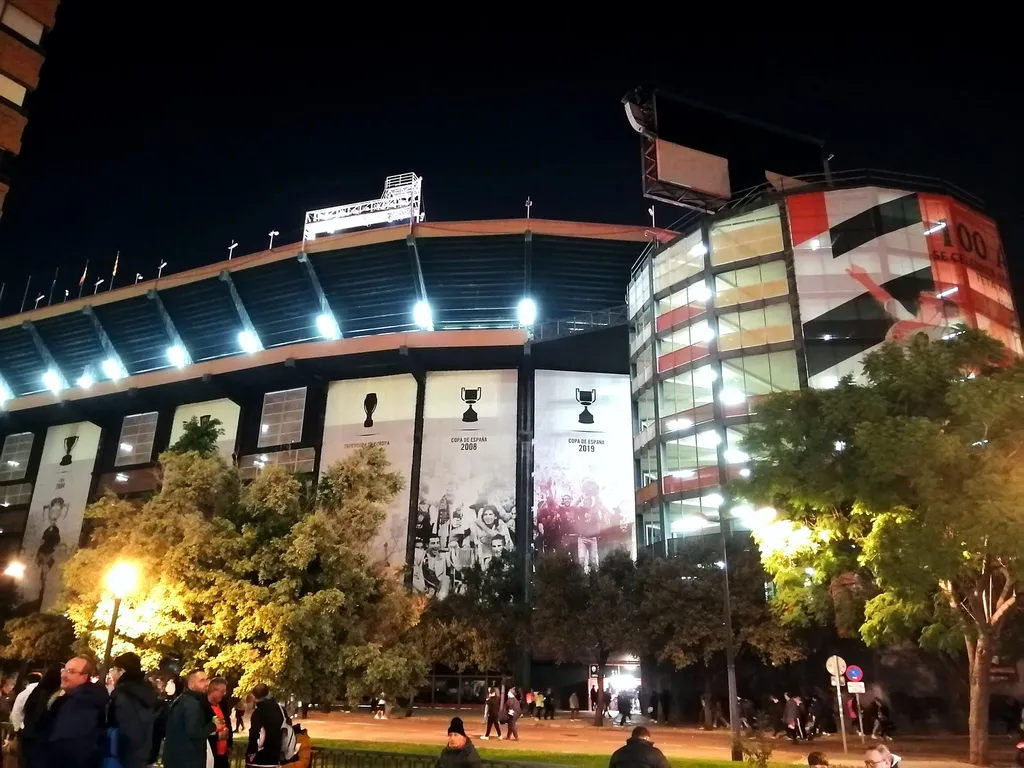 The Mestalla stadium exterior at night, decorated with Valencia CF trophy banners before a La Liga match