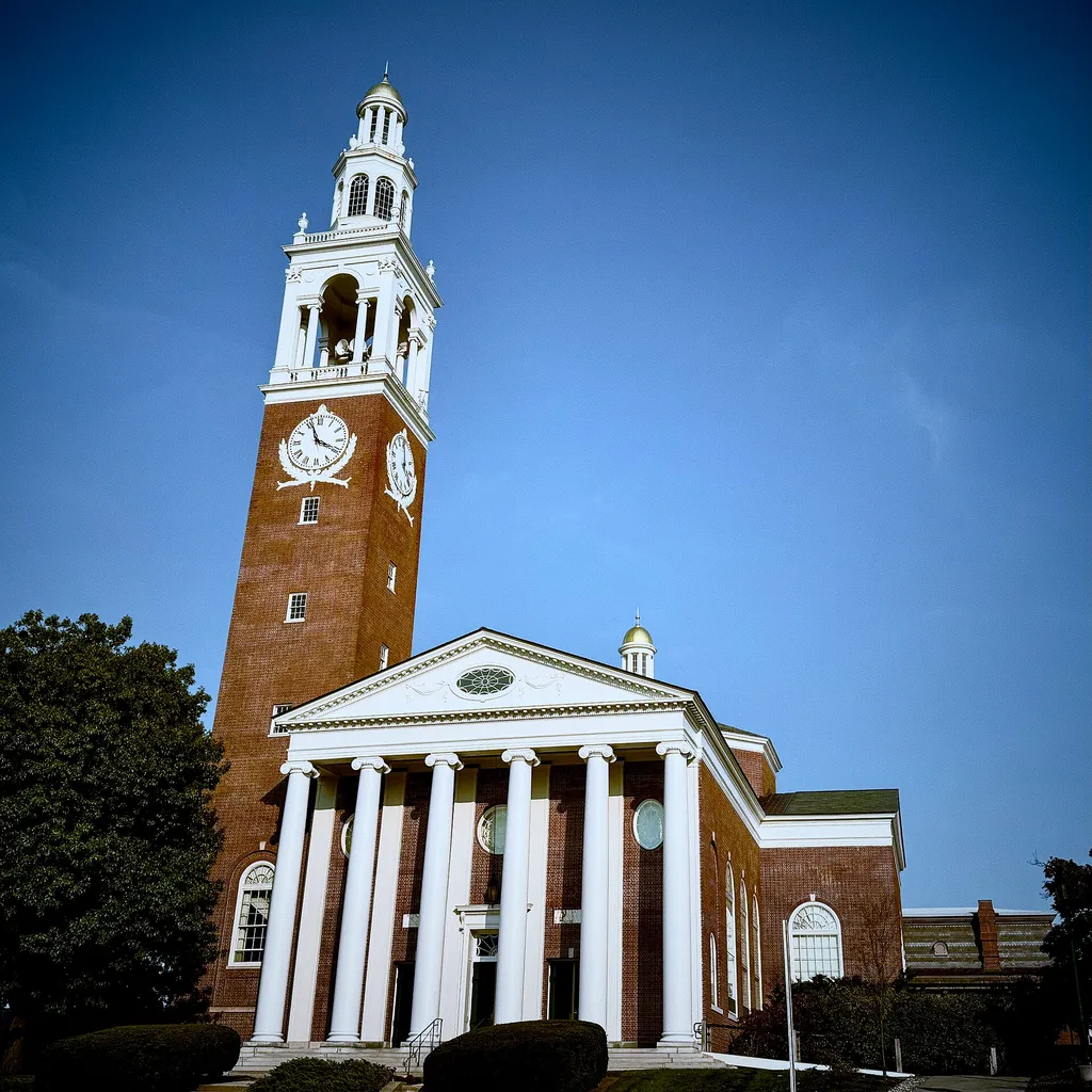 Ira Allen Chapel's brick clock tower and white-columned facade on the University of Vermont campus in Burlington, Vermont.