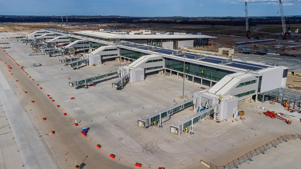 Aerial view of the Western Sydney International Airport terminal under construction, with aerobridges and apron